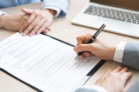 Close up of business people hands signing contract agreement document on clipboard at desk in office, lawyer or businessman putting signature filling corporate legal paperwork form.