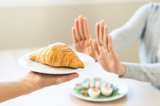 Ketogenic, Low carb, Intermittent Fasting diet woman push out, deny hand push out, deny butter croissant bread on plate, choose green vegetable salad, eat food for good healthy, getting weight loss.