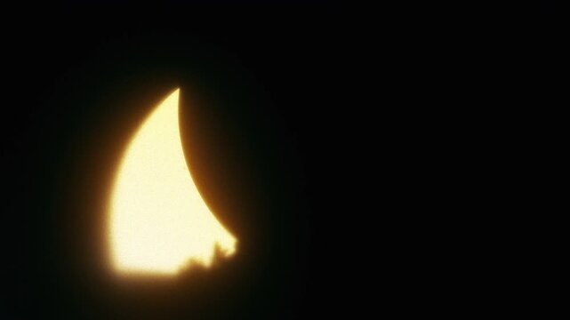 Solar eclipse over a silhouetted hillside with the moon crossing in front of a glowing golden sun, seamless loop for astronomy and space backgrounds