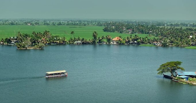 Aerial view of the Alleppey backwaters in Kerala, featuring lush green islands,  village houses, and calm waterways, showcasing the scenic beauty of this popular tourist destination in South India.