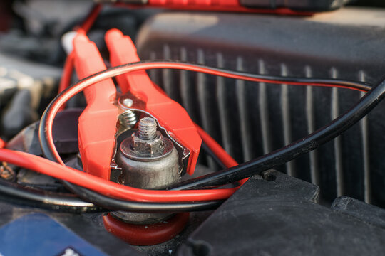 Red jumper cable clamp on a positive car battery terminal