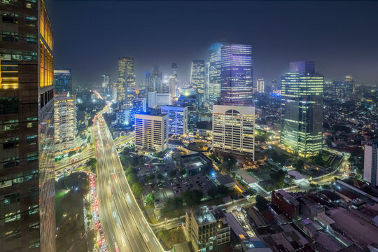 Night aerial view of the illuminated skyscrapers and heavy traffic on a major highway in Jakarta's central business district, Indonesia. Cityscapes background