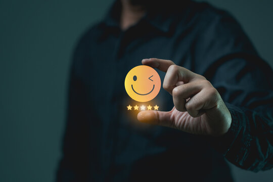Hand Holding Smiley Face Icon With Wink And Five Star Rating Symbol Representing Positive Feedback And Customer Satisfaction