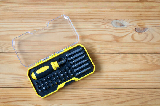 Screwdriver set in yellow case on wooden table, home repair tools for maintenance, assembly, construction and DIY projects