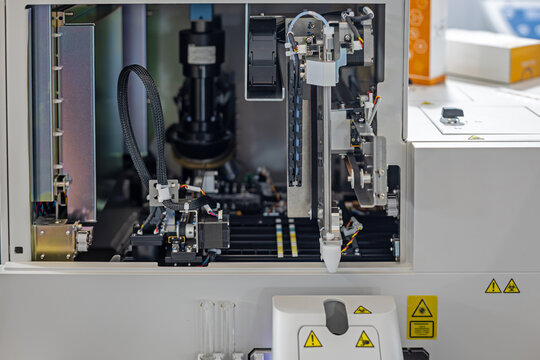 Automated Laboratory Analyzer with Robotic Pipetting System. Open laboratory analyzer reveals robotic pipetting components, motors, wiring and sample tubes inside a precision diagnostic machine.