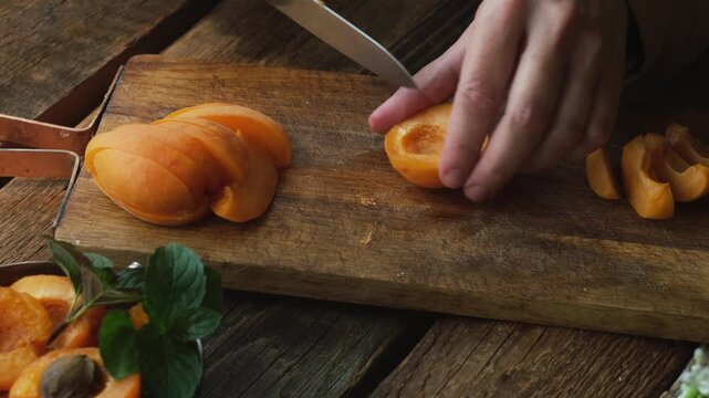 Hands cutting fresh apricots with a knife. Summer seasonal fruits.