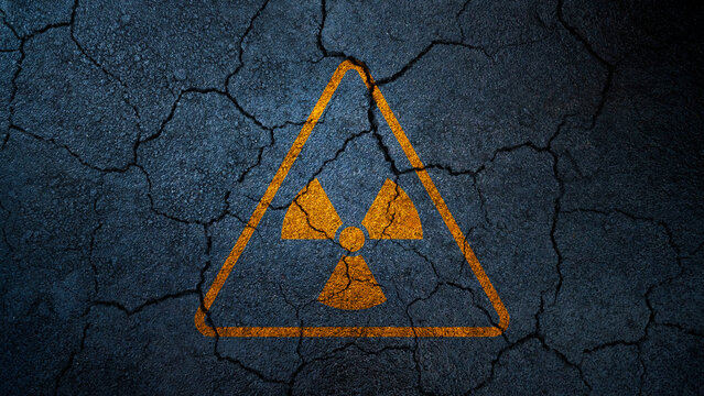 Yellow radioactive hazard symbol painted on a dark, cracked asphalt texture, symbolizing nuclear danger and post-apocalyptic ruin. Nuclear concept