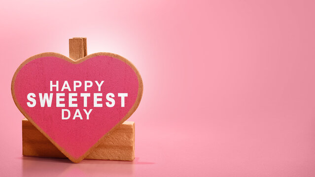 Happy Sweetest Day text on a pink wooden heart clipped with a clothespin against a pink background with copy space. Happy Sweetest Day Concept