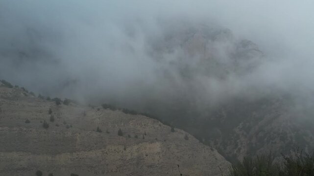 Fog covers rolling hills creating soft white atmospheric layer under overcast conditions for weather nature landscape atmosphere drone photography footage commercial ready footage