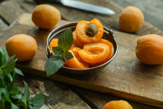 Apricots garnished with mint leaves on wooden cutting board