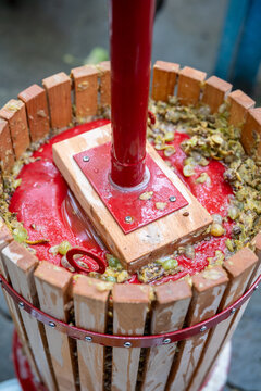Artisanal wine extraction details shown. Traditional wooden wine press in operation with foam and flowing liquid highlights