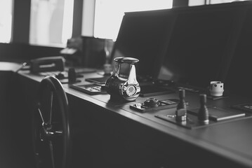 Black and white photo of wheelhouse, bridge of a modern new build superyacht, with wooden wheel, throttle controls, radar, auto-pilot, navigation and other control panels © lupiphoto