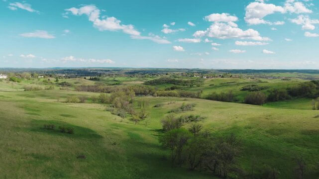 Aerial of bright blue sky and cumulus clouds over green countryside near Mandan, North Dakota, with rolling grassland.