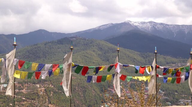 Rows of Prayer Flags Frame a View of Forested Mountains and Snow-Capped Peaks Above Bhutanese Valley