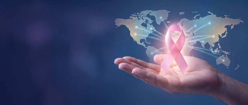 Pink awareness ribbon glowing above an open hand with a world map background, representing breast cancer awareness, global healthcare, support, prevention and medical advocacy. Banner, copy space