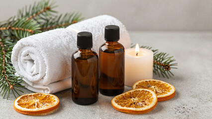 Fototapeta premium Christmas aromatherapy still life with amber bottles, towels, candle and dried oranges