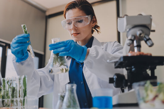Scientists in lab coats work with plants in a modern lab, focusing on research and experimentation under bright, sterile conditions.