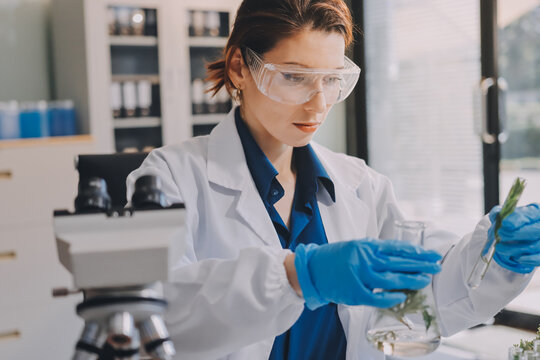 Scientists in lab coats work with plants in a modern lab, focusing on research and experimentation under bright, sterile conditions.