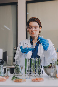 Scientists in lab coats work with plants in a modern lab, focusing on research and experimentation under bright, sterile conditions.