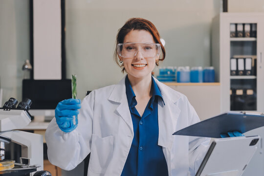 Scientists in lab coats work with plants in a modern lab, focusing on research and experimentation under bright, sterile conditions.