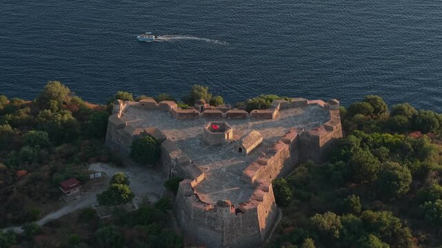 Aerial view of the historic triangular Porto Palermo Castle surrounded by lush greenery and the deep blue sea in Porto Palermo, Qarku i Vlores, Albania.