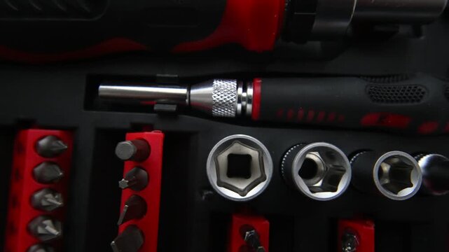 Close up top down view of professional screwdriver tool kit set with various metal bits and sockets arranged in organized case.