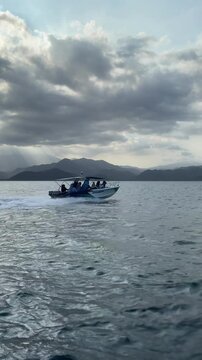 Speedboat cruising across open ocean water toward scenic tropical mountains