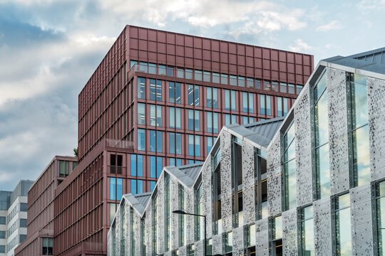 View of the modern architecture at King's Cross St. Pancras, featuring a striking red-toned office building and contemporary structures with patterned facades in London, England, United Kingdom.