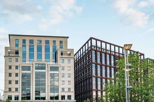 View of modern office buildings near King's Cross St. Pancras featuring a light stone facade and a dark metal grid structure under a clear blue sky in London, England, United Kingdom.