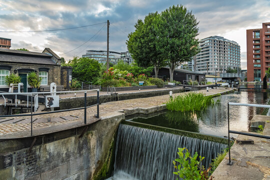 View of the canal lock at King's Cross St. Pancras with flowing water, stone pathways, and modern architecture in the background in London, England, United Kingdom.