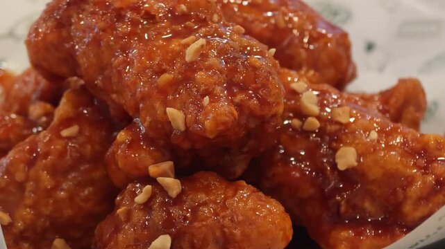 Korean fried chicken in spicy yangnyeom sauce with peanuts 4K video