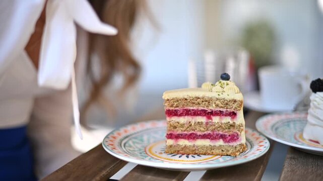 Woman eating delicious layer cake with berry filling using metal fork in cafe.