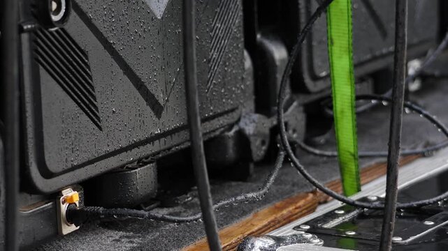 Close-up of wet black electrical panel with green wire and water droplets. Rainy outdoor scene creating severe short circuit hazard, fire risk, electrocution, and electrical safety danger. 4k video
