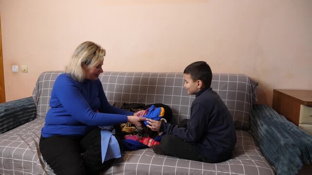 Woman and boy sort clothes together and pass garments to each other during an ongoing household activity.