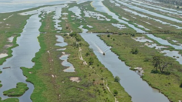 Aerial view of Karavasta Lagoon with winding waterways and lush green wetlands in Divjake, Fier County, Albania.