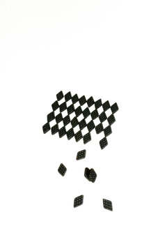 Black licorice candy falls from a geometric checkerboard pattern