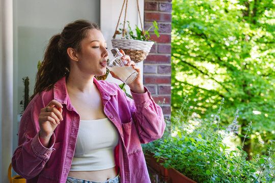 Woman drinks a probiotic beverage on an urban balcony