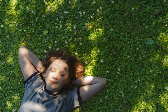 A girl rests on green grass enjoying a peaceful moment in nature