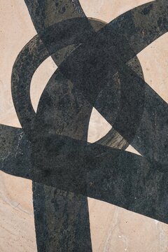 Black abstract brushstroke creates geometric shape on beige canvas