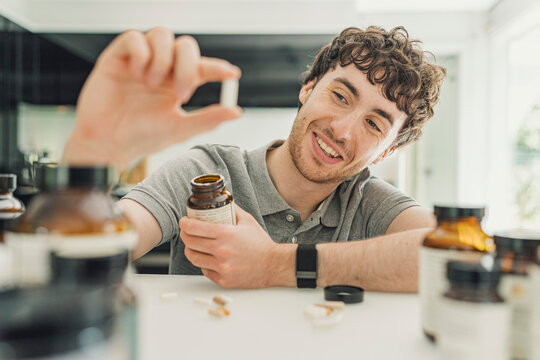 Happy male examines a gut microbiome supplement pill at home