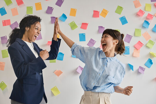 Female colleagues celebrate success with a high five in the office