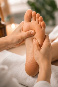 Close-up of therapist hands giving a professional reflexology foot massage to a woman in a spa salon. Wellness, relaxation, alternative medicine, and body skin care treatment concept