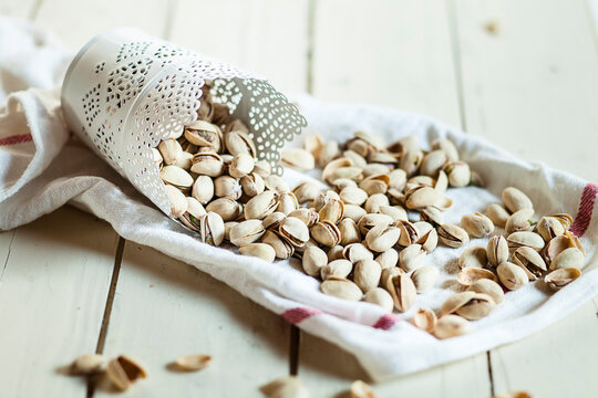 Cup of roasted and salted pistachios on kitchen towel