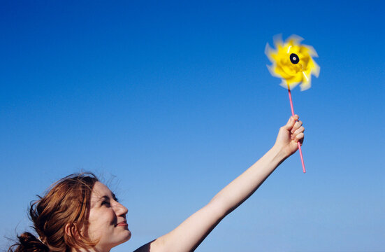 Young woman holding pin wheel into air