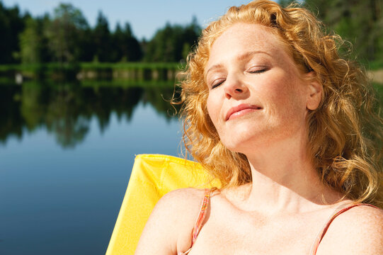 Italy, South Tyrol, Woman sunbathing on jetty by lake