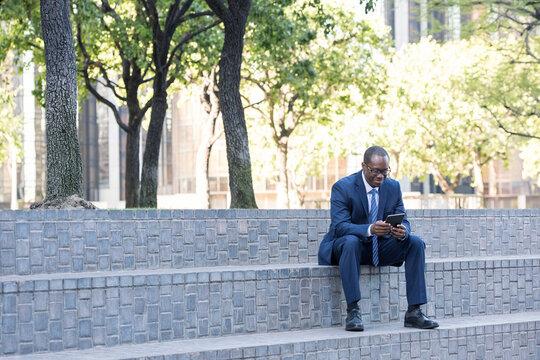 Businessman sitting on stairs using tablet