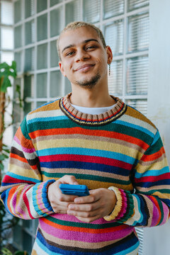 A smiling young businessman holds a phone in a green office