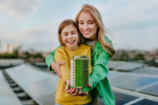 Mother and daughter hold a sustainable building model on a roof