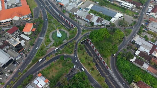 Aerial view of the Statue of Dewa Ruci roundabout with surrounding traffic and urban greenery in Kecamatan Kuta, Bali, Indonesia.