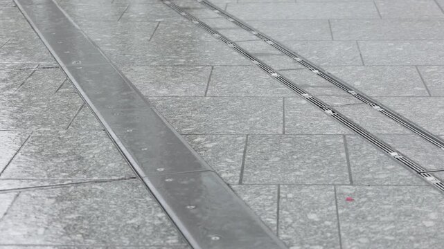 Rain falling on wet tiled pavement surface outdoors